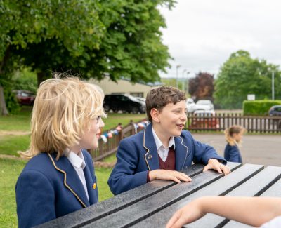 Rookwood Lower School students talking to each other on a bench outside