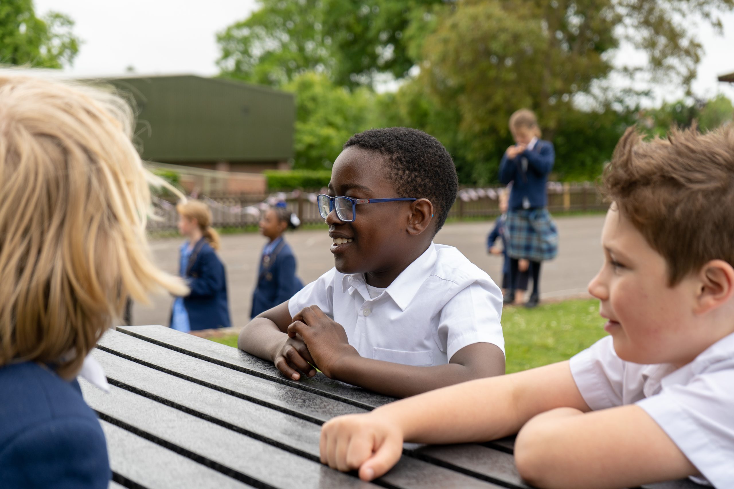 Rookwood School pupils speaking to each other outside on a bench