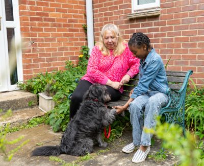 Rookwood School student sat on a bench next to a teacher with a dog in front of them both