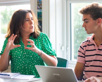 A Rookwood School teacher talking to a student working on a laptop